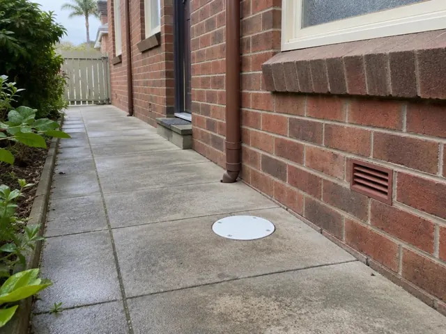 Brick side path with a round drain cover, dry paving and garden edging in Eastwood
